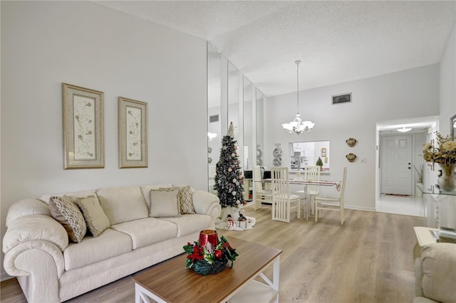 living room featuring hardwood / wood-style floors, high vaulted ceiling, a textured ceiling, and a notable chandelier