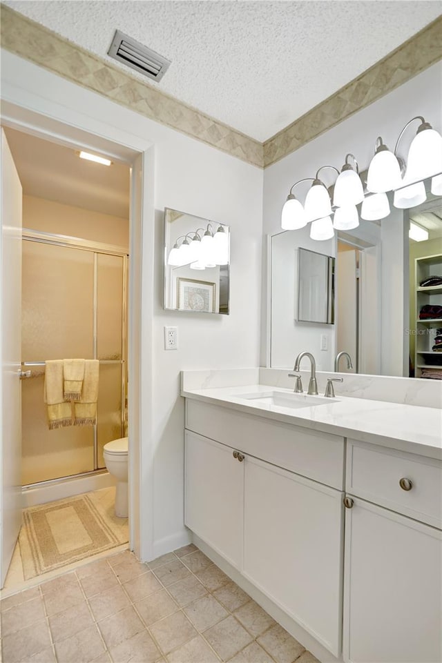 bathroom with vanity, a shower with door, tile patterned flooring, toilet, and a textured ceiling