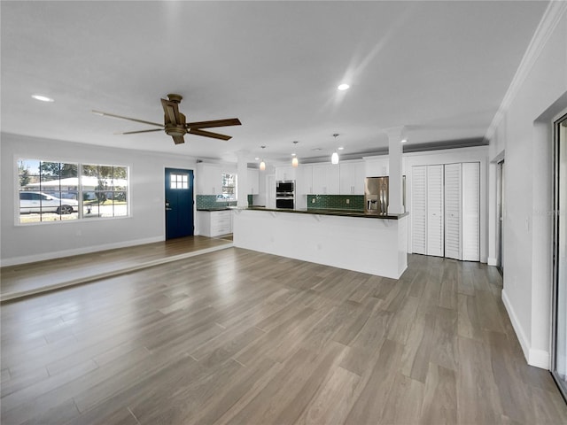 unfurnished living room with ceiling fan, light wood-type flooring, and crown molding