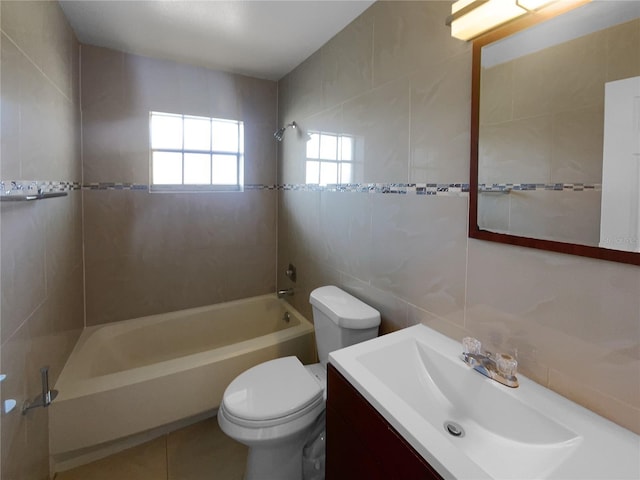 full bathroom with vanity, tile patterned floors, tiled shower / bath, toilet, and tile walls