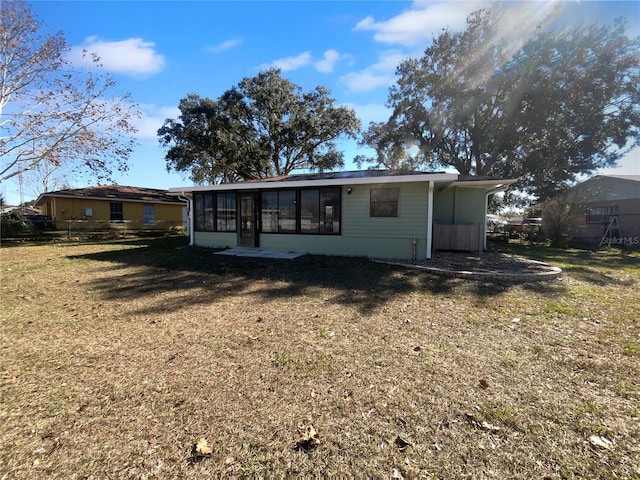 rear view of house with a lawn and a sunroom