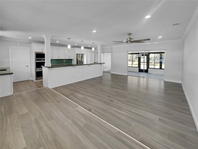 unfurnished living room with ceiling fan, light wood-type flooring, and ornamental molding