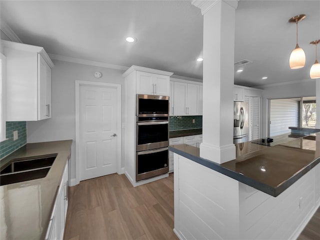 kitchen featuring decorative backsplash, appliances with stainless steel finishes, white cabinetry, and hanging light fixtures