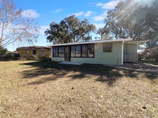 back of house with a sunroom and a lawn