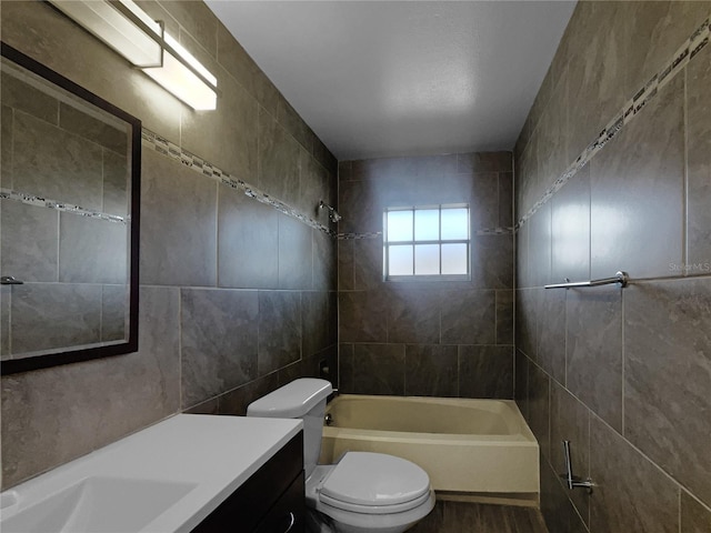 full bathroom with vanity, toilet, tile walls, and tiled shower / bath combo