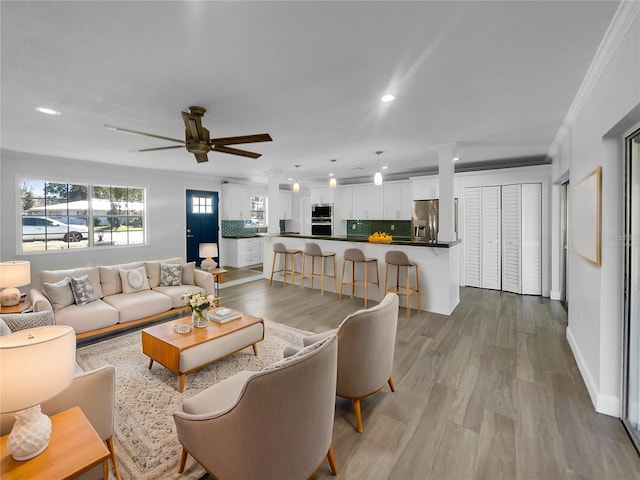 living room with light wood-type flooring, ceiling fan, and crown molding