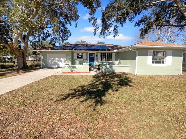 14912 SW 35th Cir, Ocala, FL 34473 - ranch-style house with concrete driveway, a garage, roof mounted solar panels, and a front lawn