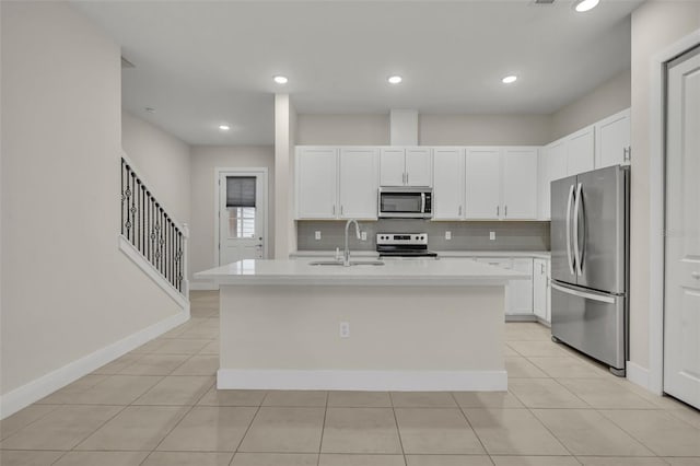 kitchen with a kitchen island with sink, sink, white cabinets, and appliances with stainless steel finishes