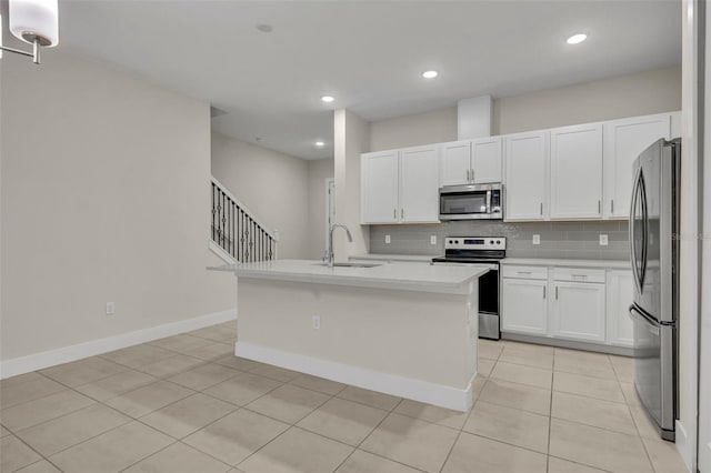 kitchen featuring white cabinets, appliances with stainless steel finishes, a kitchen island with sink, and sink