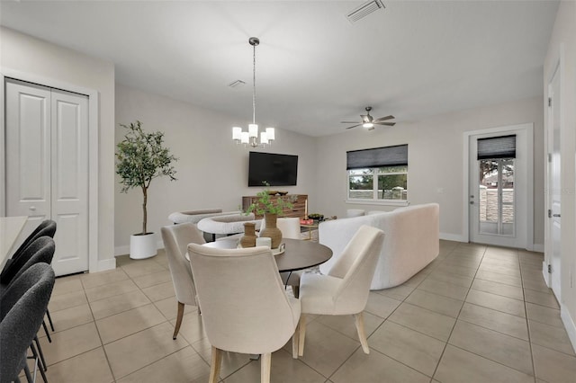 tiled dining room with ceiling fan with notable chandelier