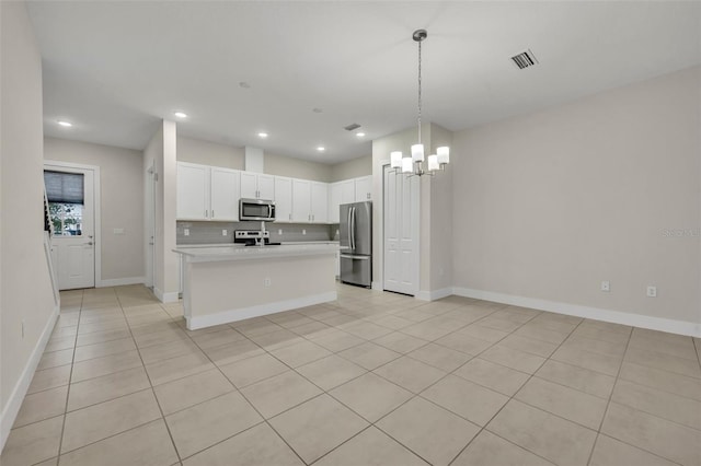 kitchen with light tile patterned flooring, stainless steel appliances, hanging light fixtures, and an island with sink