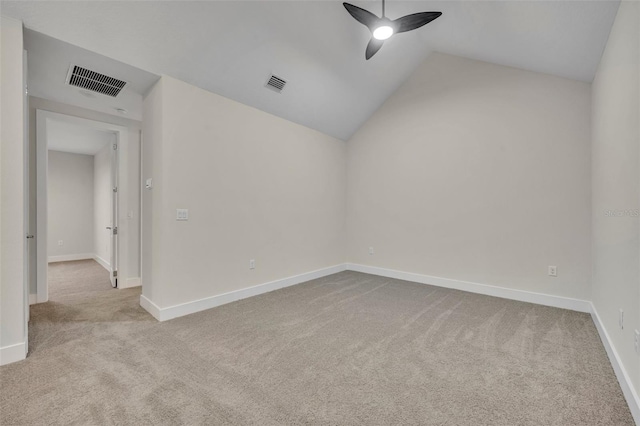 spare room with ceiling fan, light colored carpet, and vaulted ceiling