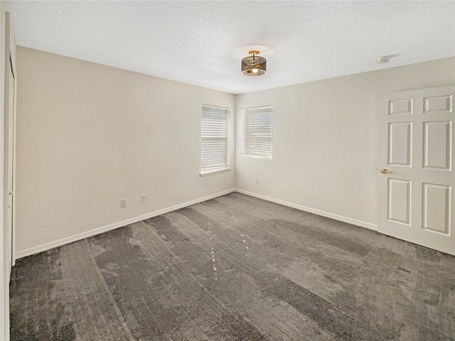 carpeted empty room featuring a textured ceiling