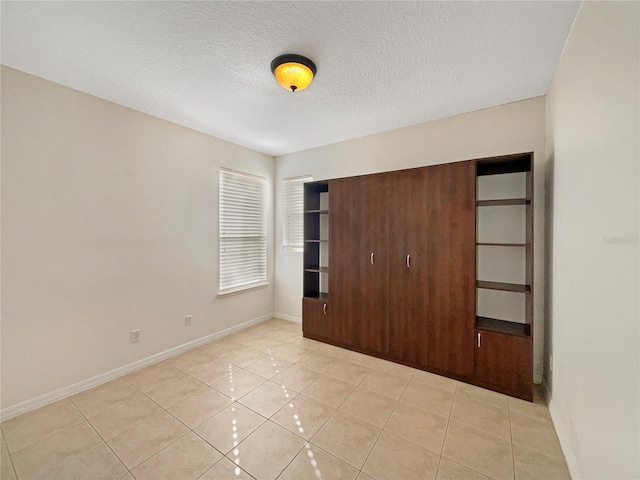 unfurnished bedroom with a textured ceiling, a closet, and light tile patterned flooring