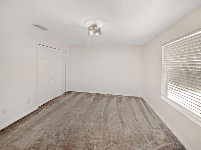 carpeted spare room with a textured ceiling