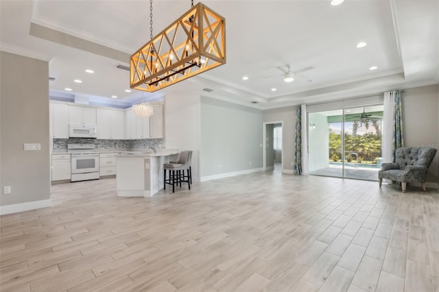 unfurnished living room featuring light hardwood / wood-style floors, a raised ceiling, ceiling fan, and crown molding