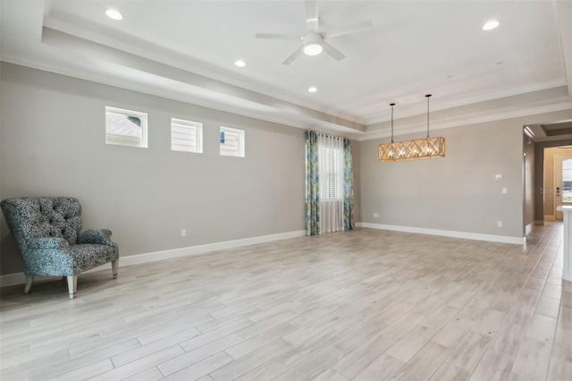 interior space with a raised ceiling, crown molding, ceiling fan with notable chandelier, and light wood-type flooring