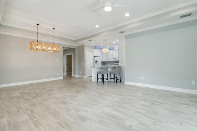 unfurnished living room featuring crown molding and ceiling fan with notable chandelier