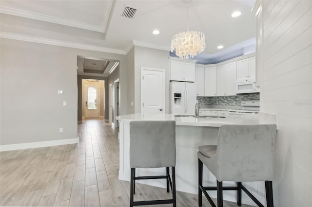 kitchen with a kitchen breakfast bar, kitchen peninsula, white cabinets, and white appliances