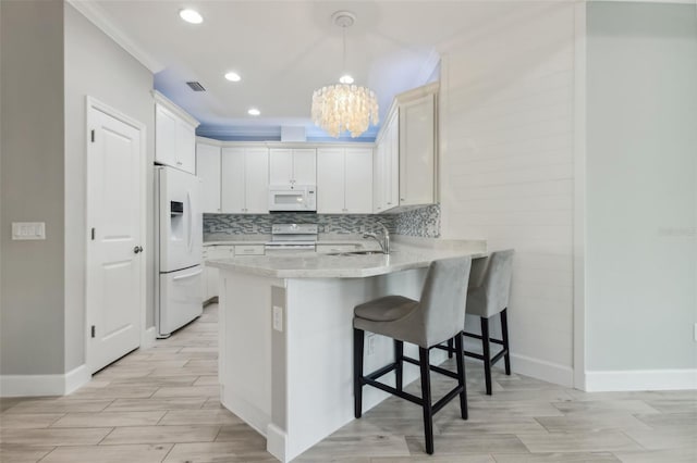 kitchen with a notable chandelier, crown molding, pendant lighting, white appliances, and white cabinets