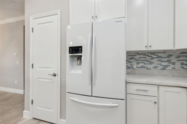 kitchen with white refrigerator with ice dispenser, decorative backsplash, white cabinets, and light stone counters