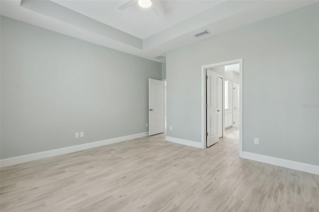 unfurnished bedroom with ceiling fan, light hardwood / wood-style flooring, and a tray ceiling