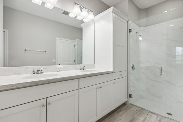 bathroom featuring wood-type flooring, vanity, and an enclosed shower