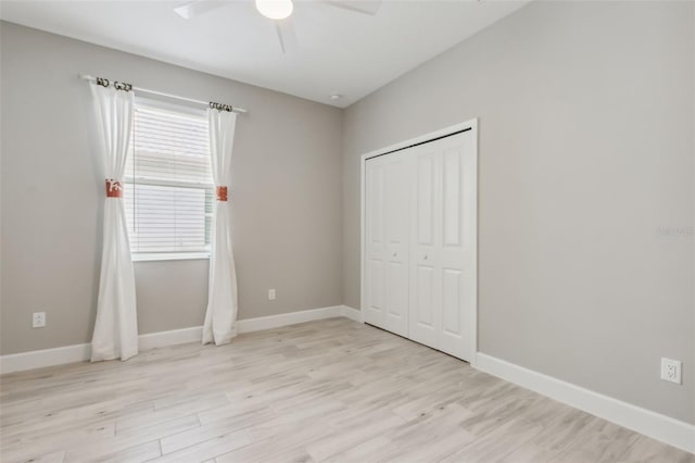 unfurnished bedroom featuring multiple windows, a closet, light hardwood / wood-style flooring, and ceiling fan