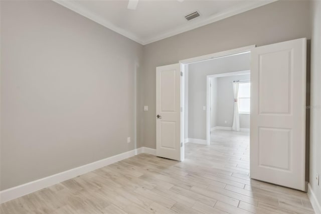 empty room featuring light wood-type flooring and ornamental molding