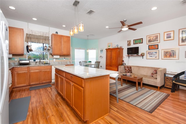 kitchen featuring pendant lighting, a kitchen island, a wealth of natural light, and ceiling fan