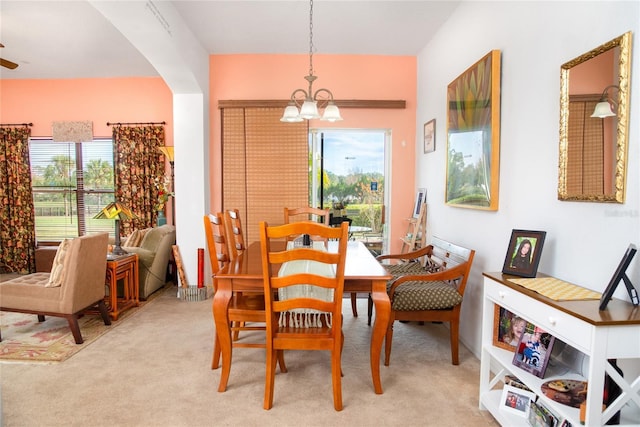 carpeted dining space with an inviting chandelier