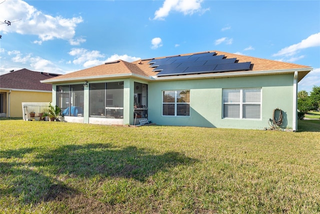 back of property featuring a sunroom, solar panels, and a yard