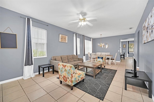 tiled living room featuring ceiling fan with notable chandelier