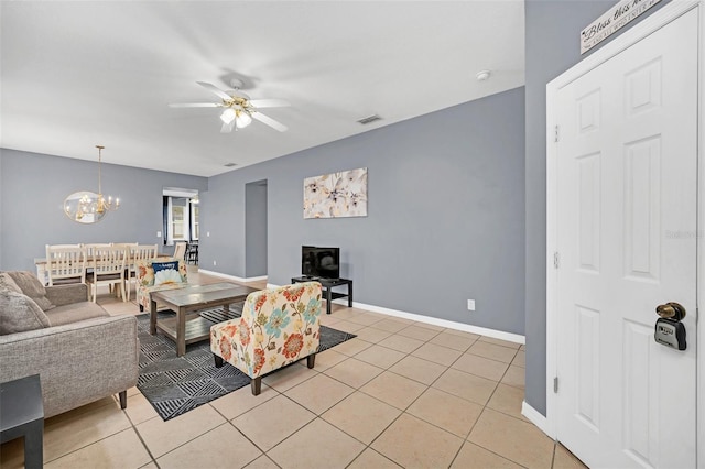 tiled living room with ceiling fan with notable chandelier