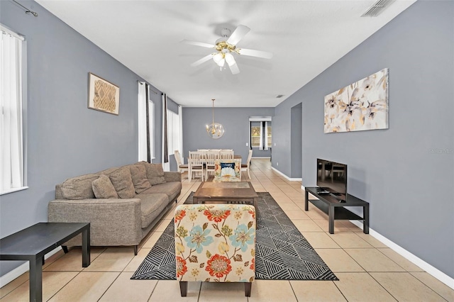 living room featuring a wealth of natural light, light tile patterned floors, and ceiling fan with notable chandelier