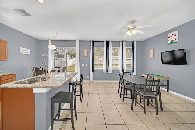 tiled dining space with ceiling fan and sink