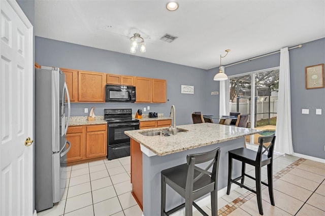 kitchen featuring black appliances, light tile patterned flooring, sink, and a kitchen island with sink