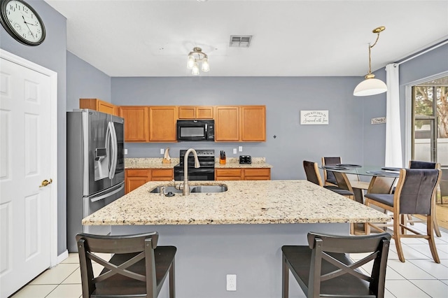 kitchen with pendant lighting, a breakfast bar area, a center island with sink, light tile patterned flooring, and appliances with stainless steel finishes