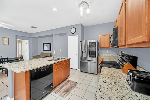 kitchen featuring sink, light stone counters, an island with sink, light tile patterned flooring, and black appliances