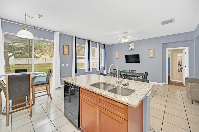 kitchen featuring ceiling fan, sink, decorative light fixtures, black dishwasher, and an island with sink