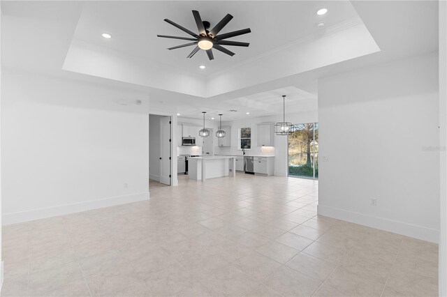 unfurnished living room with a raised ceiling, crown molding, light tile patterned floors, and ceiling fan with notable chandelier