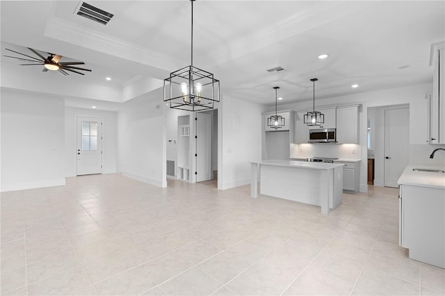 kitchen featuring ceiling fan with notable chandelier, a kitchen island, sink, and hanging light fixtures