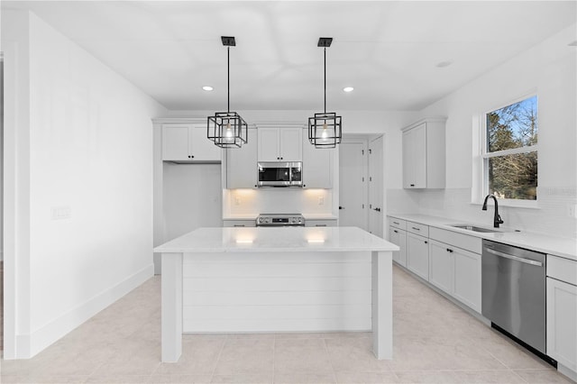 kitchen featuring light stone countertops, sink, hanging light fixtures, a kitchen island, and appliances with stainless steel finishes