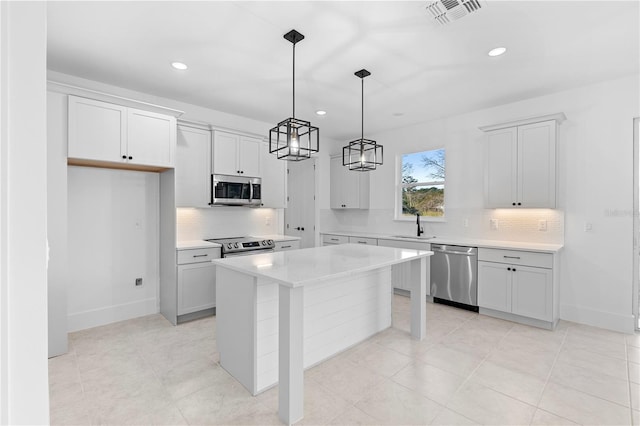 kitchen with pendant lighting, a center island, white cabinets, sink, and stainless steel appliances