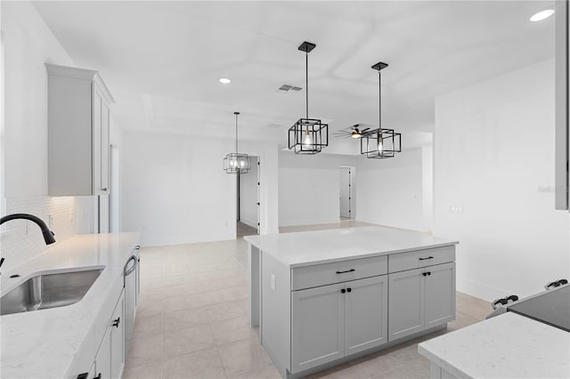 kitchen with ceiling fan, sink, a kitchen island, and pendant lighting