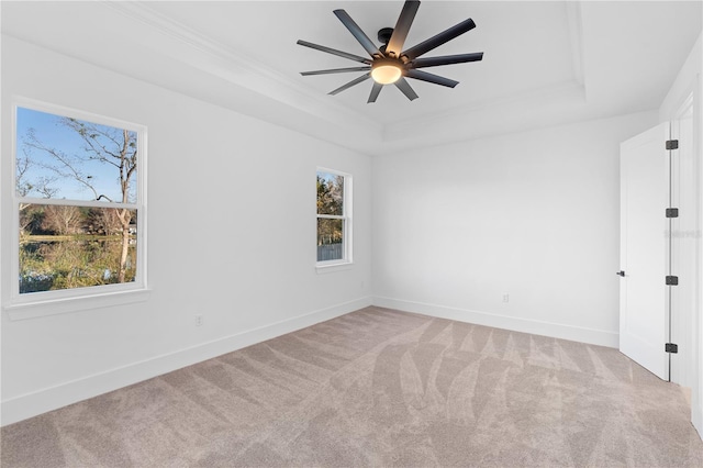 unfurnished room featuring ornamental molding, a tray ceiling, ceiling fan, and light colored carpet