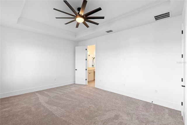 empty room featuring ornamental molding, a tray ceiling, ceiling fan, and light colored carpet