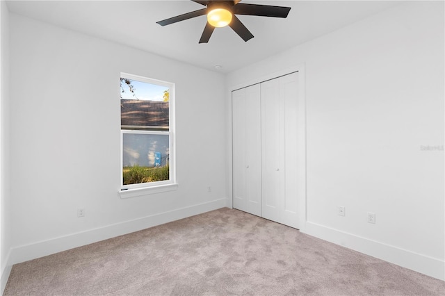 unfurnished bedroom featuring multiple windows, ceiling fan, a closet, and light carpet