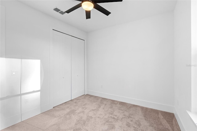 unfurnished bedroom with ceiling fan, light carpet, and a closet