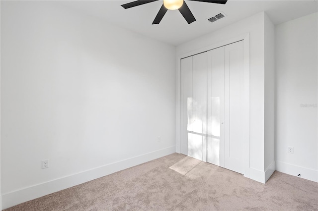 unfurnished bedroom featuring ceiling fan, light carpet, and a closet